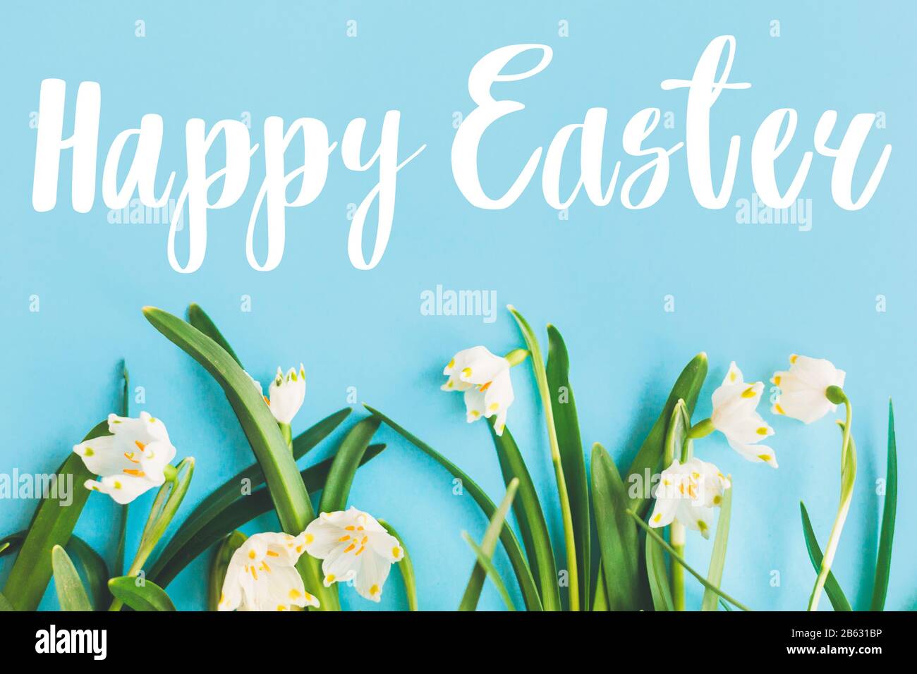 Happy Easter text on white spring flowers on bright blue flat lay ...