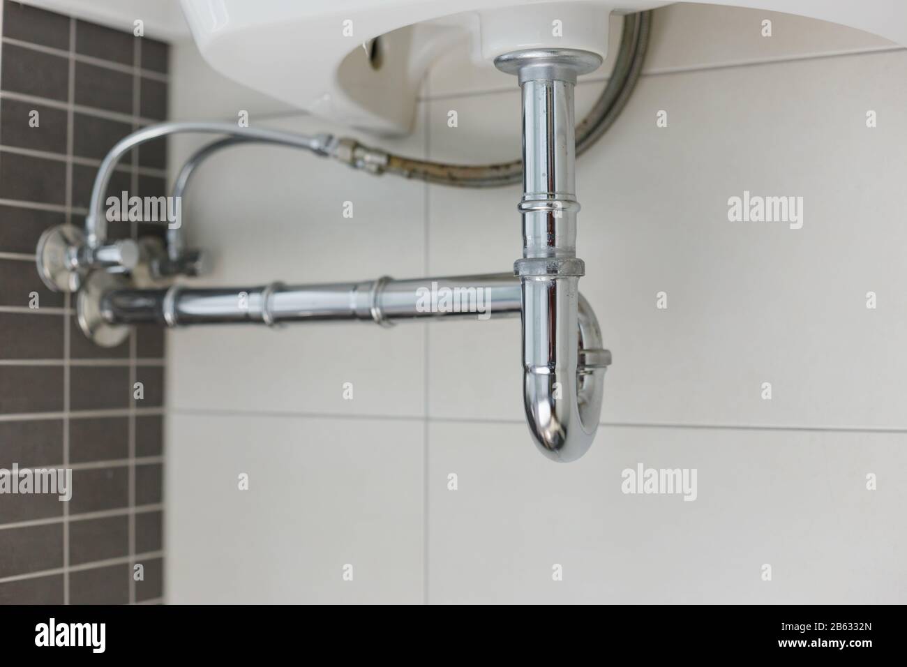 metal sink siphon and drain in white bathroom Stock Photo