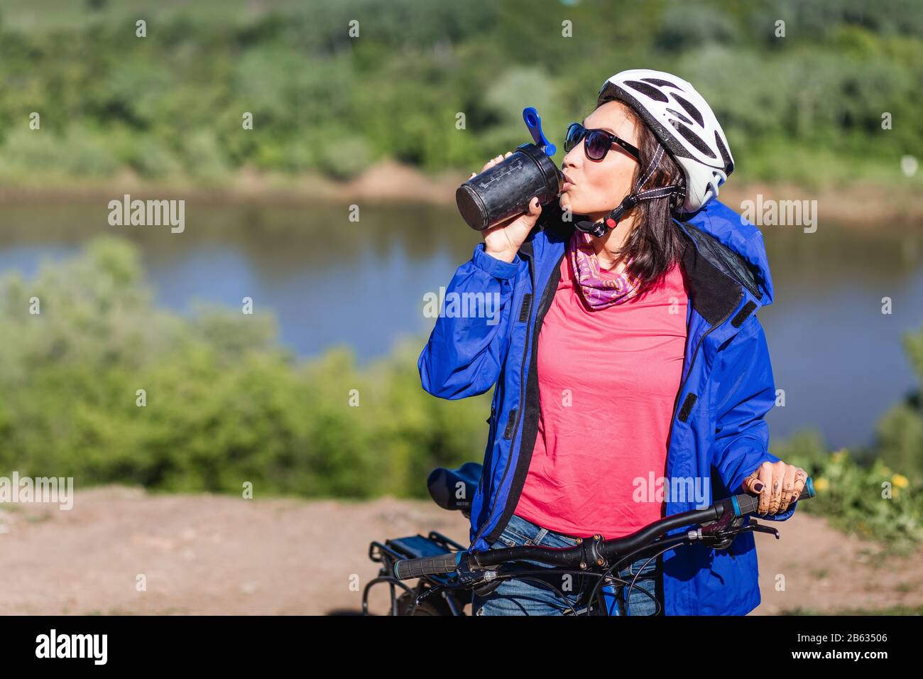 Sport young woman drinking water after doing some bicycle exercise Stock Photo