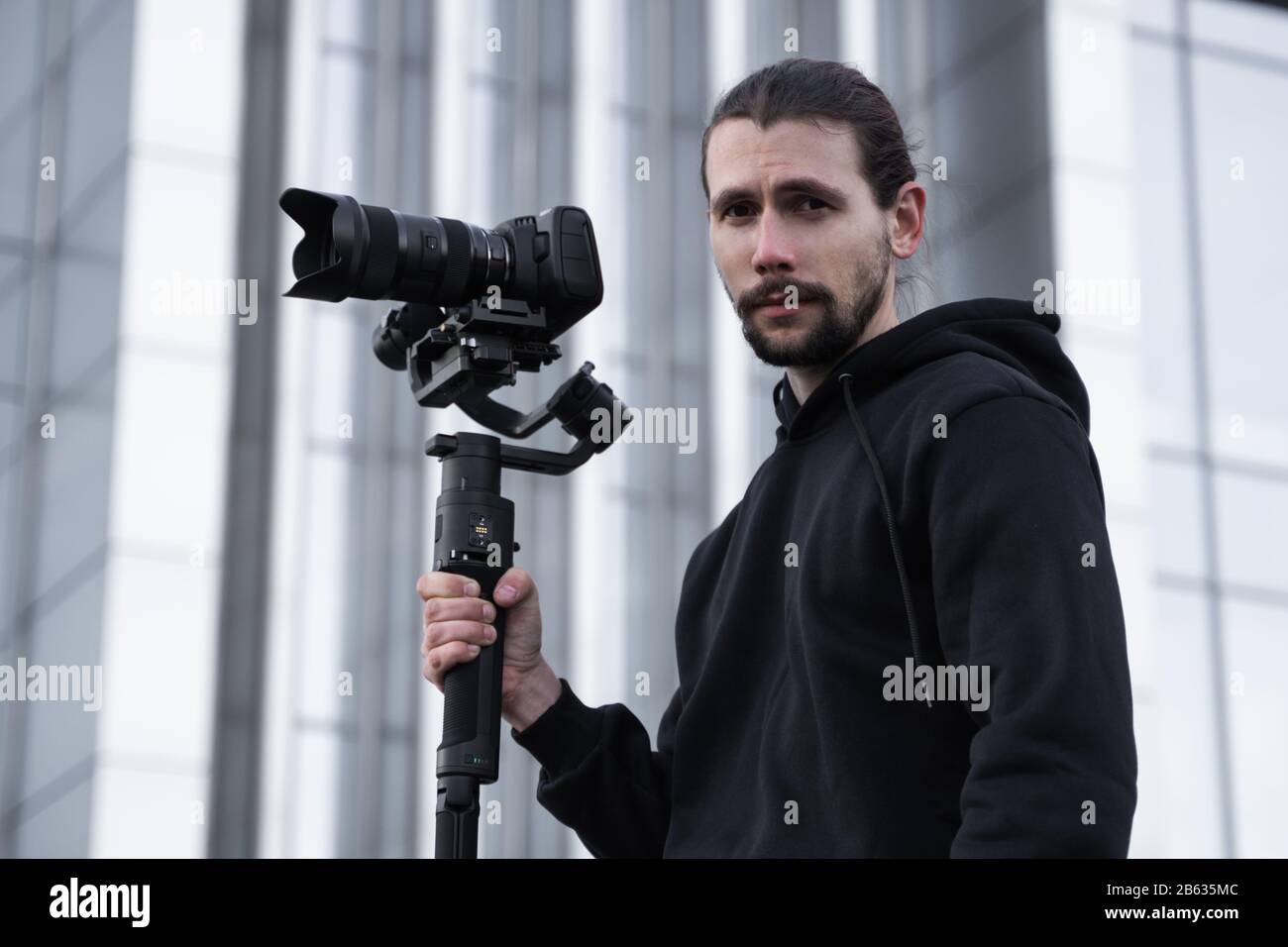 Young Professional videographer holding professional camera on 3-axis gimbal stabilizer. Pro equipment helps to make high quality video without Stock Photo