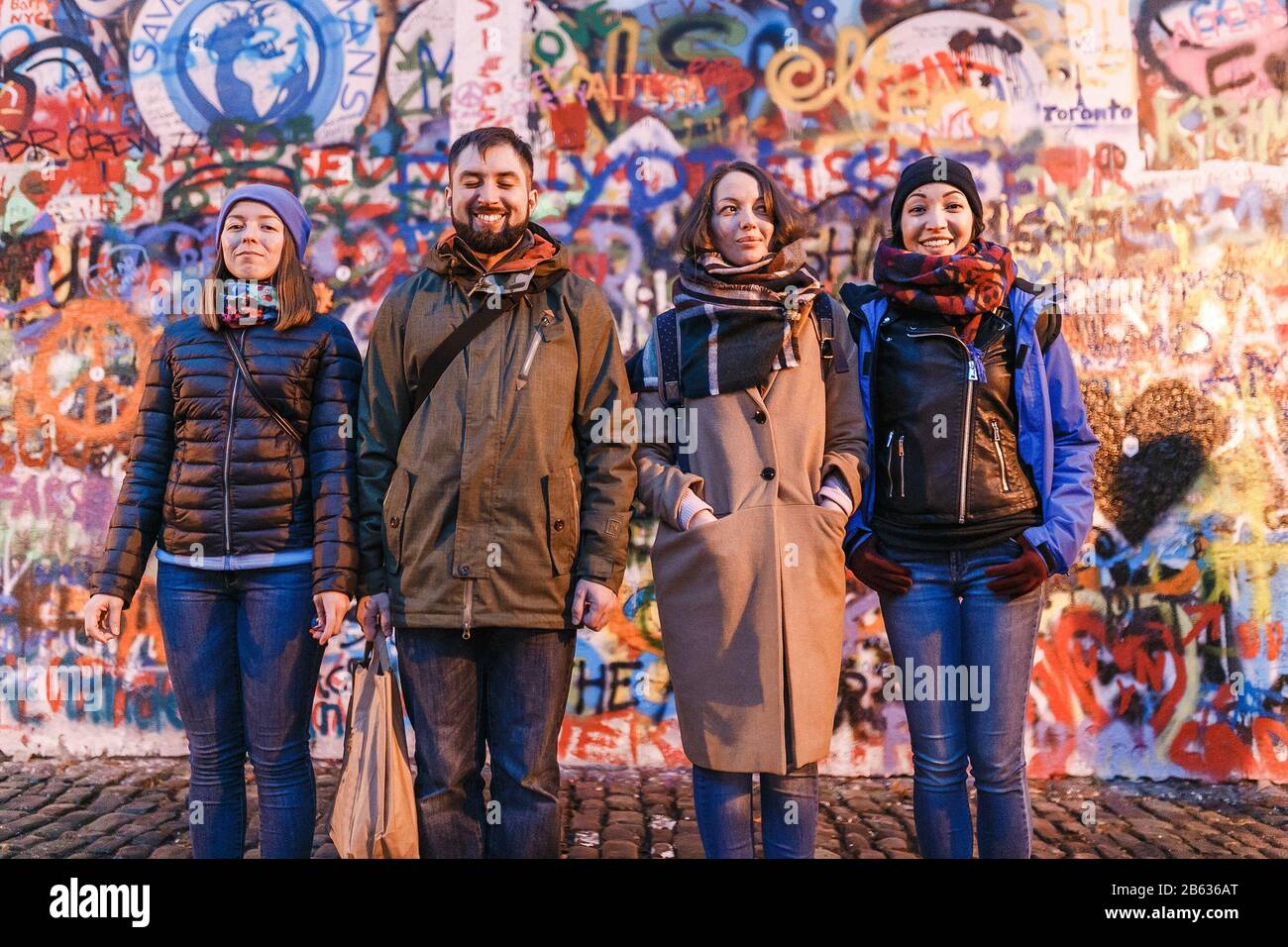 Four friends laughing against grafitti wall with unrecognizable and senseless drawings Stock Photo