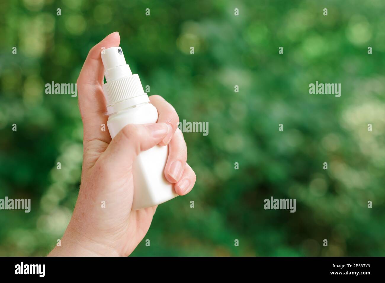 Woman using antiseptic spray outdoors in forest to protect the injury wound from infection, selective focus Stock Photo