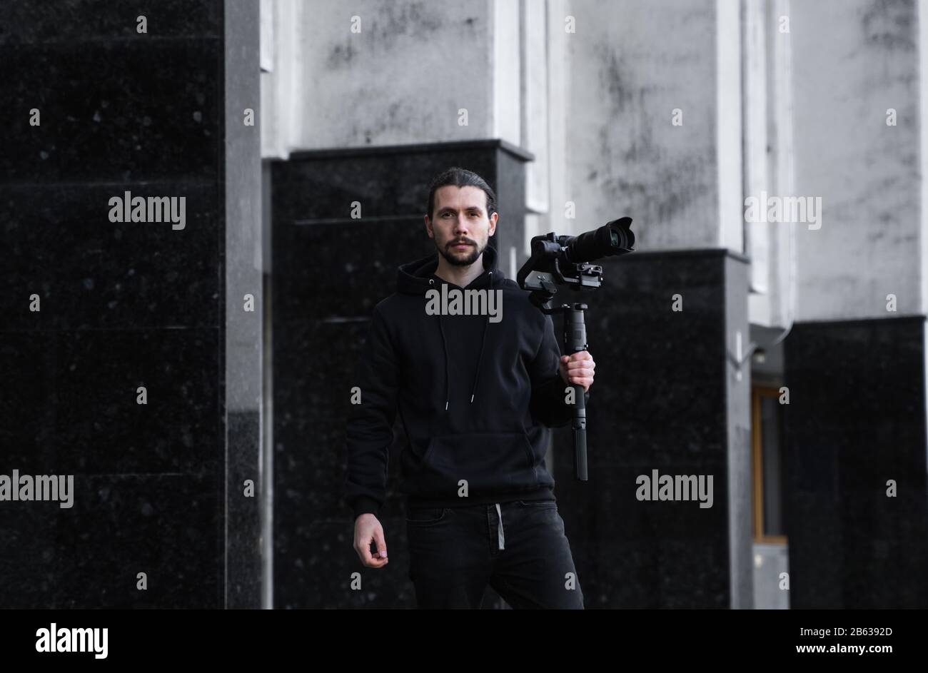 Young Professional videographer holding professional camera on 3-axis gimbal stabilizer. Pro equipment helps to make high quality video without Stock Photo