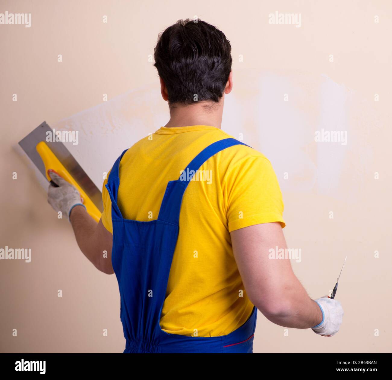 The young contractor employee applying plaster on wall Stock Photo