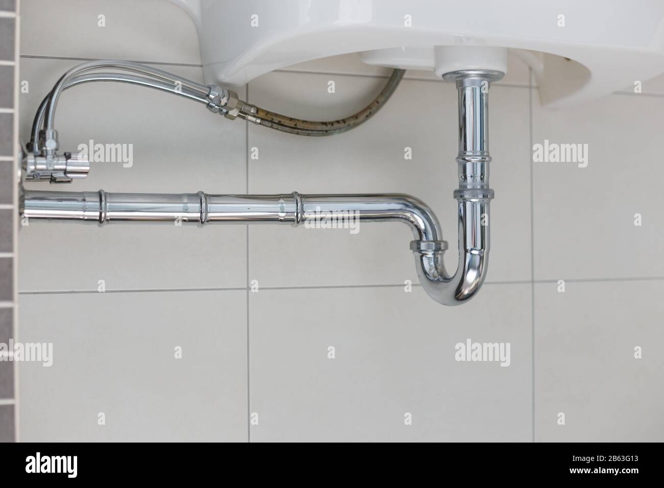 metal sink siphon and drain in white bathroom Stock Photo
