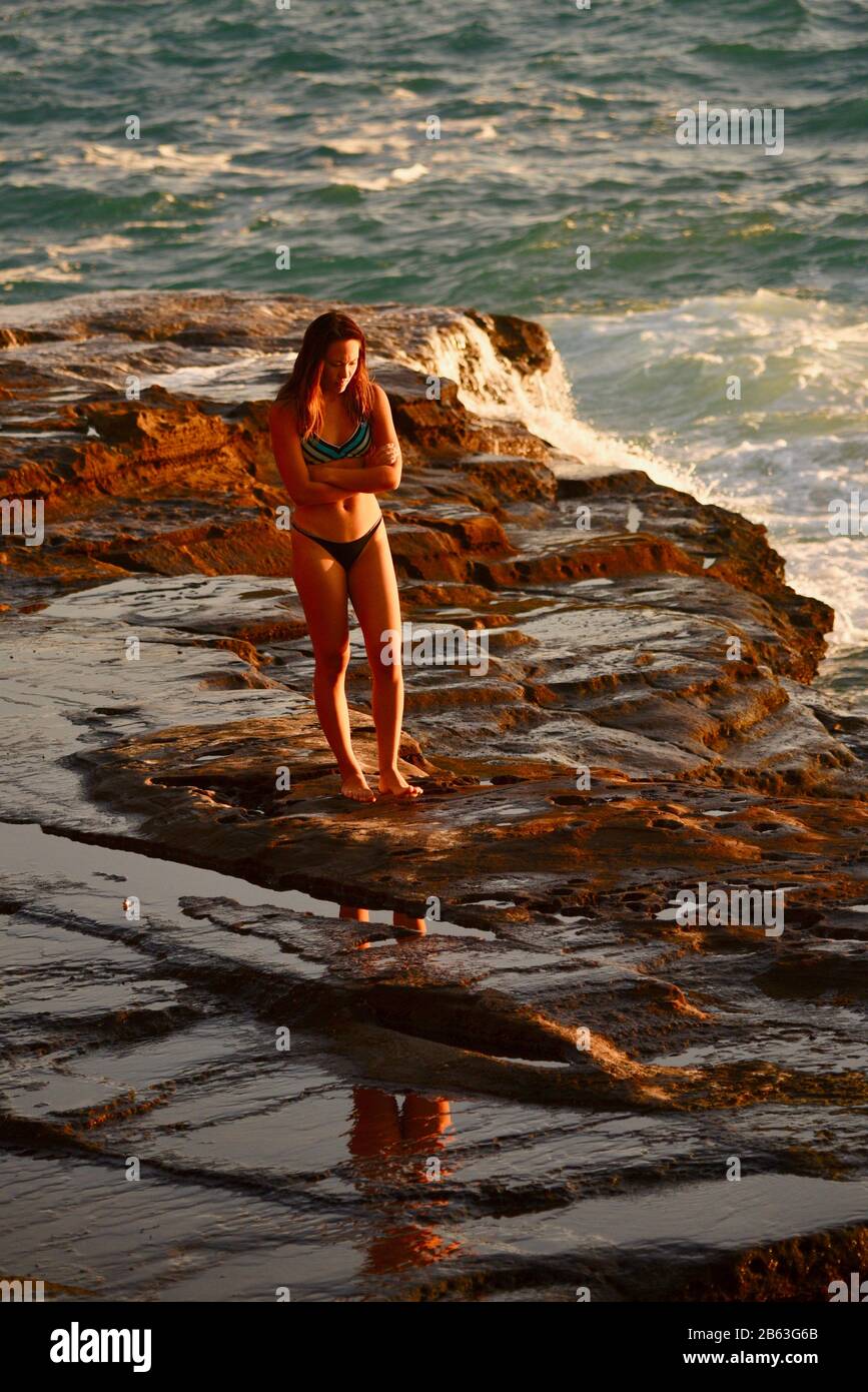 Young attractive woman watching sunset on cliffs at China Walls on east side of Honolulu, Oahu Island, Hawaii, USA Stock Photo