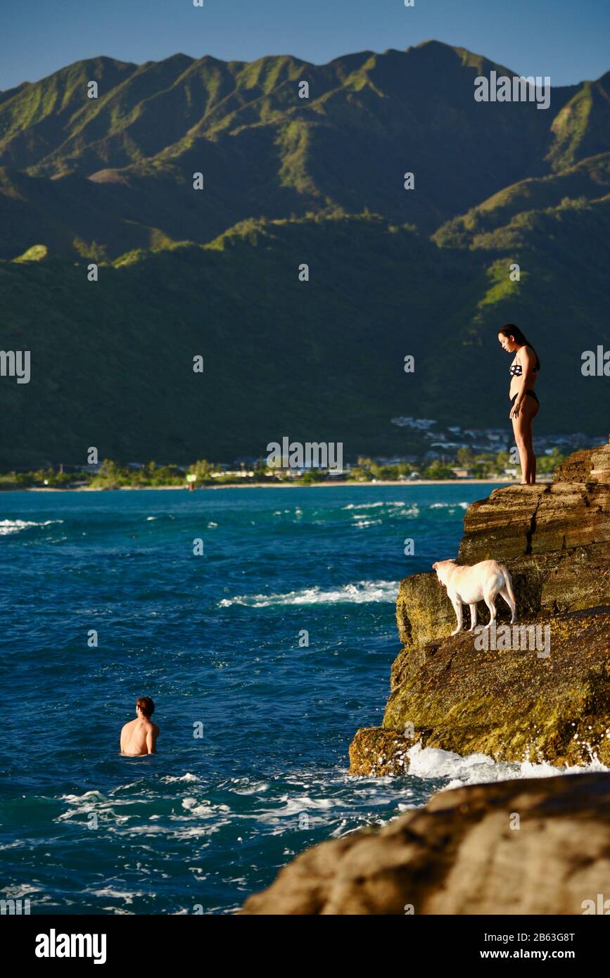 Young attractive woman watching sunset on cliffs at China Walls on east side of Honolulu, Oahu Island, Hawaii, USA Stock Photo