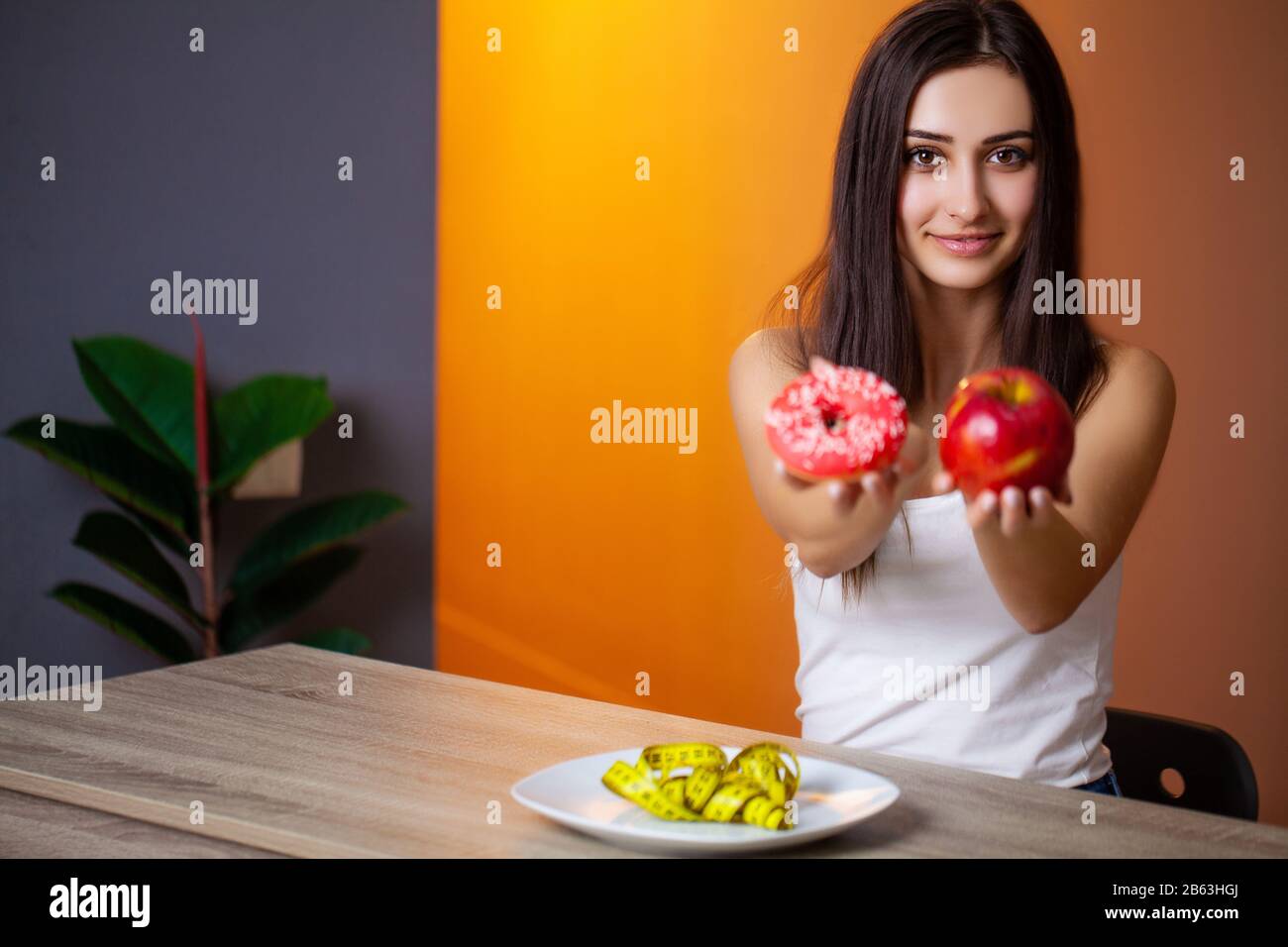 Portrait of a young beautiful girl who makes a choice between healthy food and harmful Stock Photo