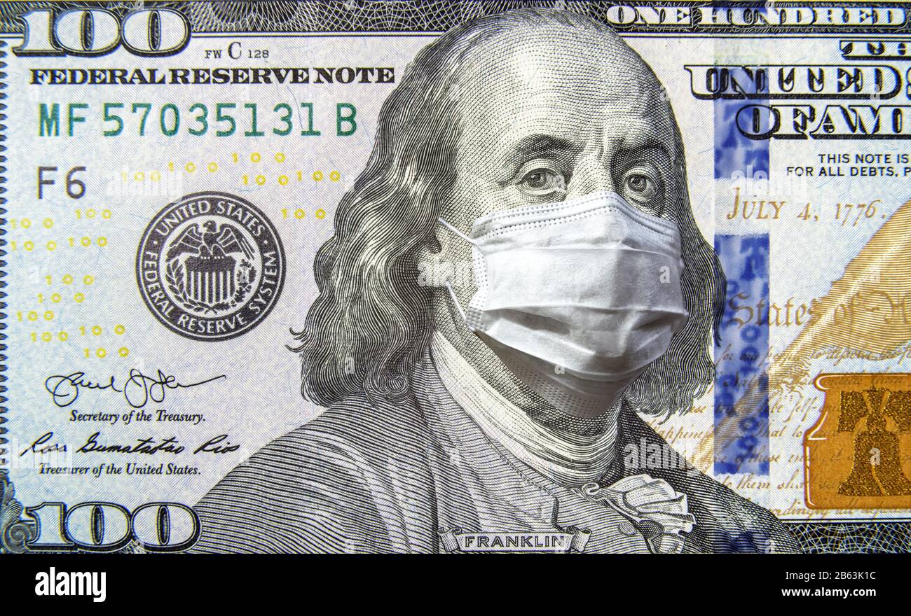 COVID-19 coronavirus in USA, 100 dollar money bill with face mask. Coronavirus affects global stock market. World economy hit by corona virus outbreak Stock Photo