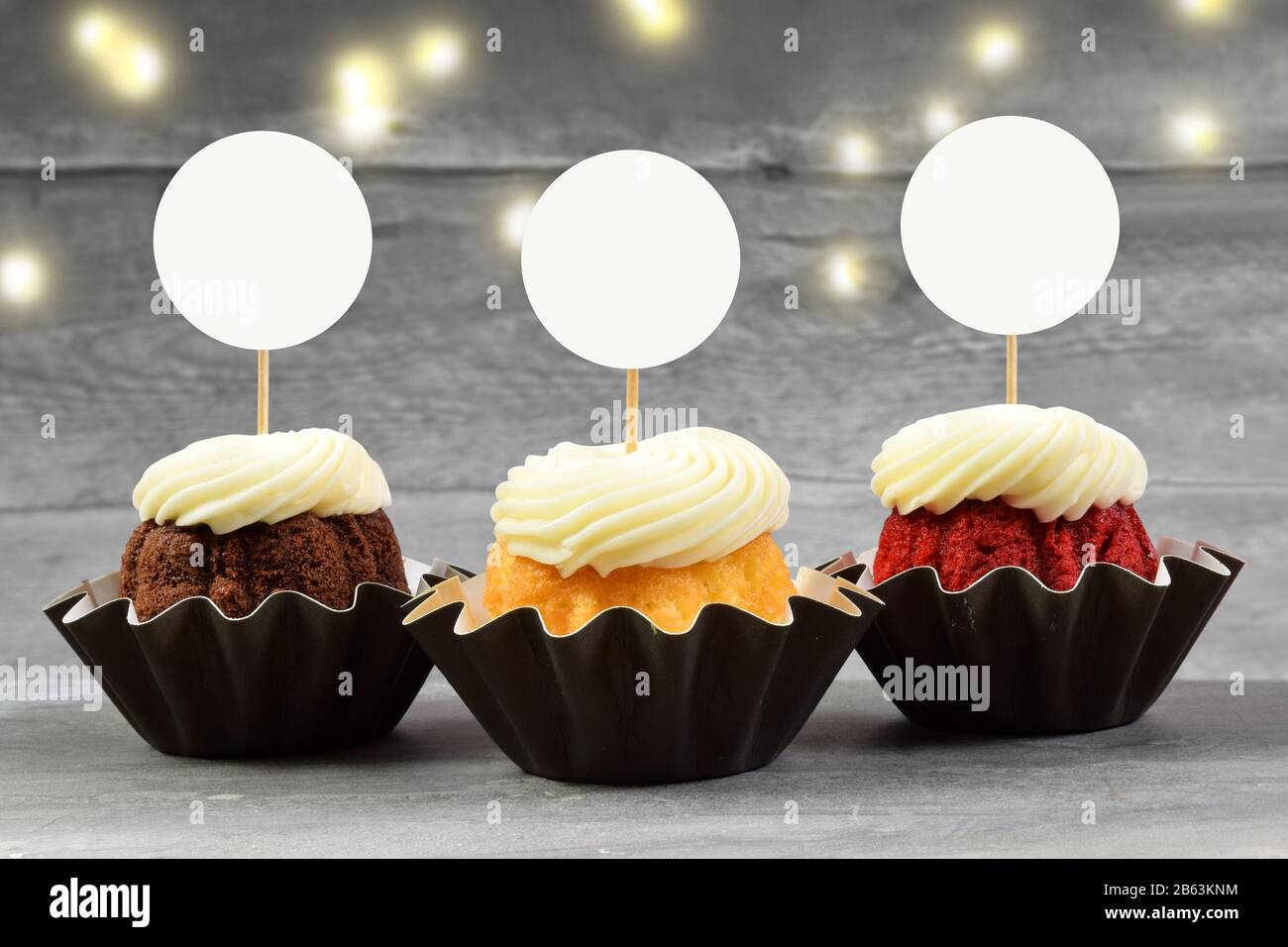 Download This Cupcake Topper Mock Up Features Three Delicious Gourmet Cupcakes On A Weathered Gray Wood Background Golden Lights Shine In The Background Of Th Stock Photo Alamy