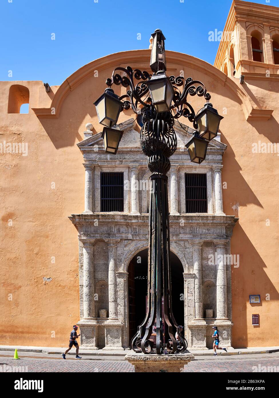 Church entrance with street lamp and runners in Cartagena, Colombia Stock Photo