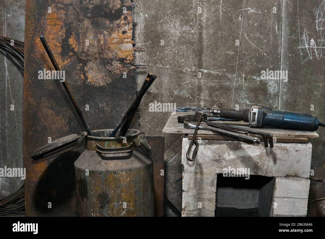 industrial still life - tools on the pedestal and metal workpieces hardened in a can against a gray concrete wall background Stock Photo