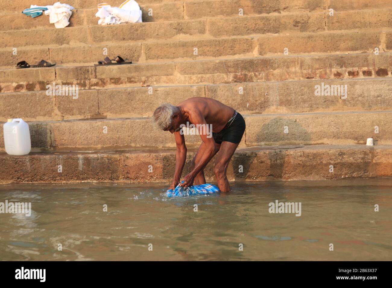 Old man wash clothes at Ganga River Stock Photo