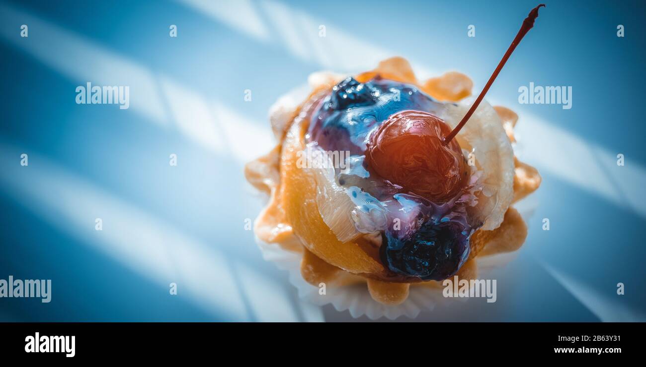 Cake basket with fruits and red cherry on the dark blue table Stock Photo