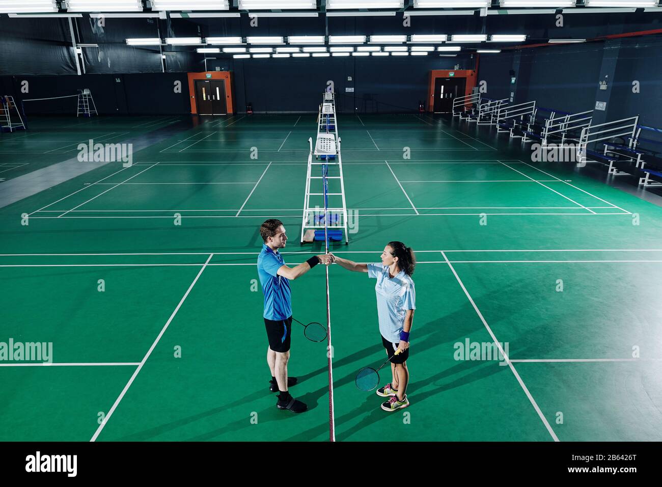Young male and female badminton players shaking hands after training in