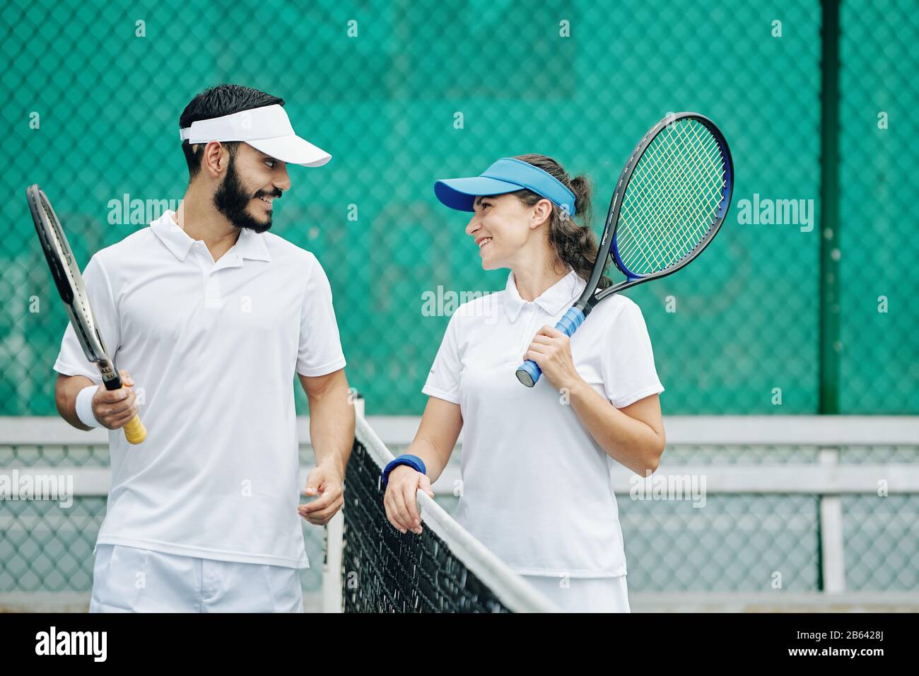 Happy young couple in white uniform enjoying playing tennis together Stock Photo