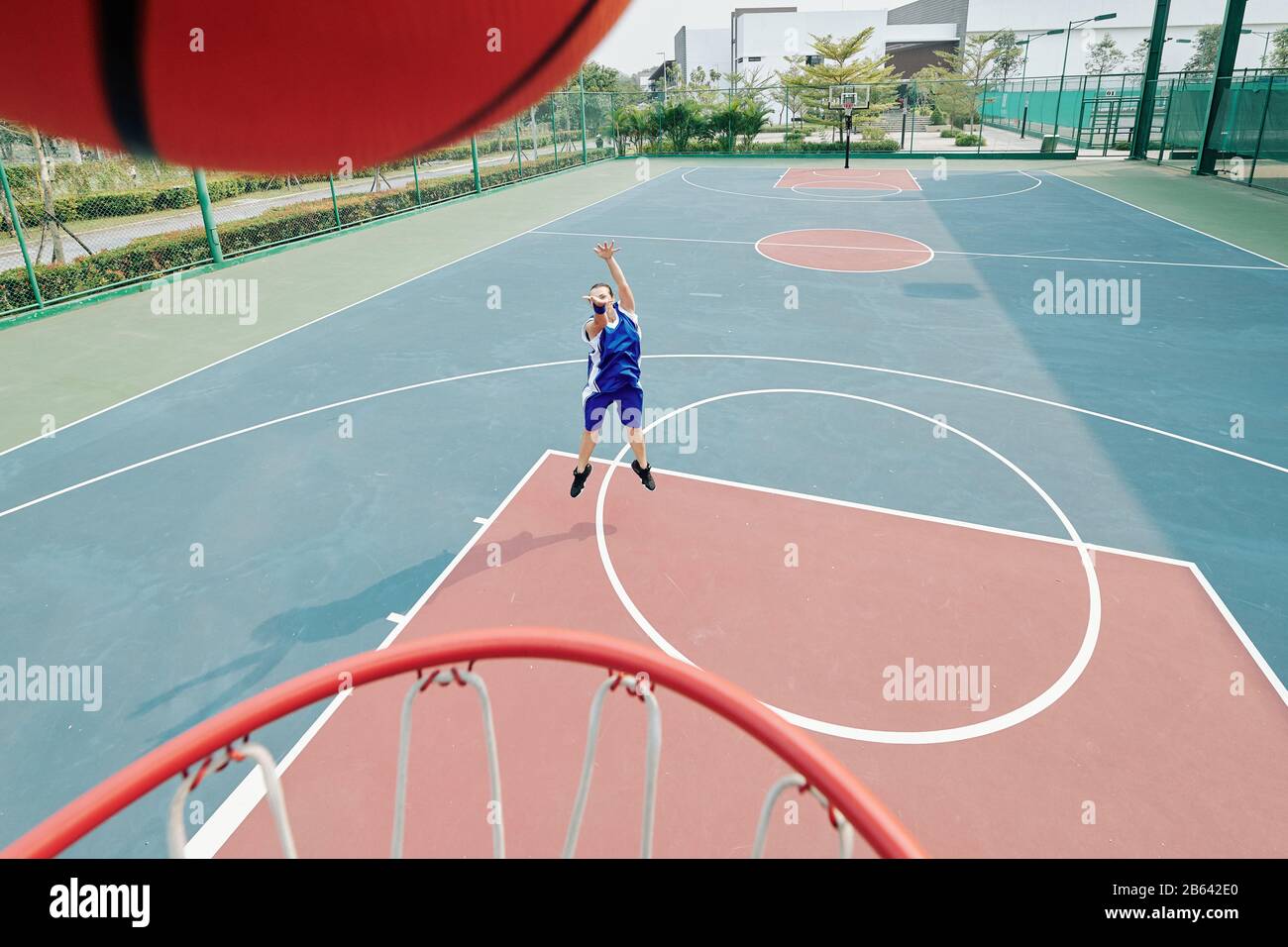 Female professional basketball player throwing ball in basket when playing on outdoor court Stock Photo