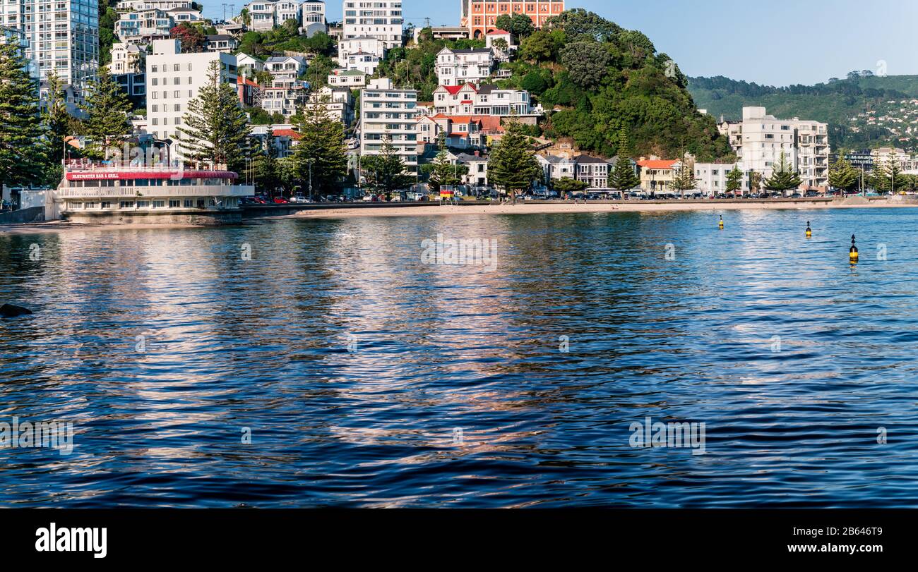 A calm Summer morning at Oriental Bay, Wellington, New Zealand sees the apartment buildings and houses reflected in the waters in the Bay. Stock Photo