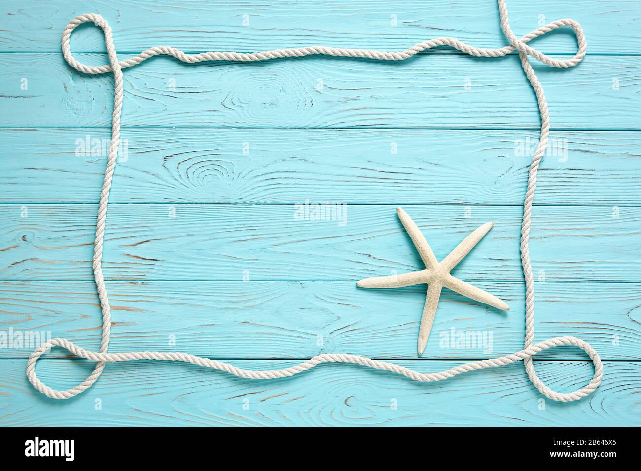 Frame made of white rope on a wooden blue background. Summer time sea vacation concept. Place for your text. Stock Photo