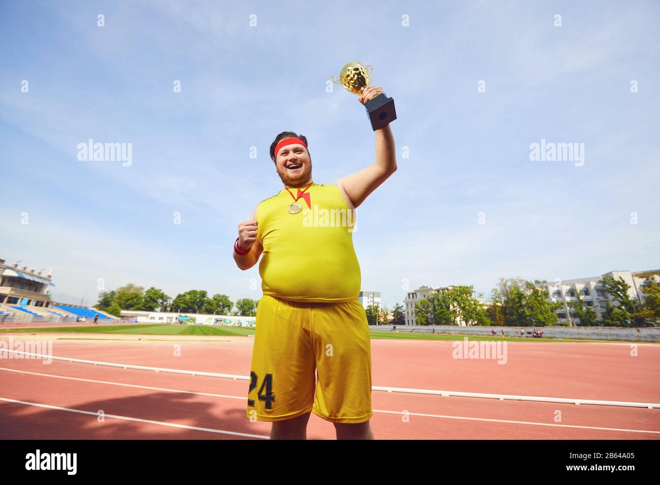 A fat man with a winner's cup in his hands at the stadium. Stock Photo