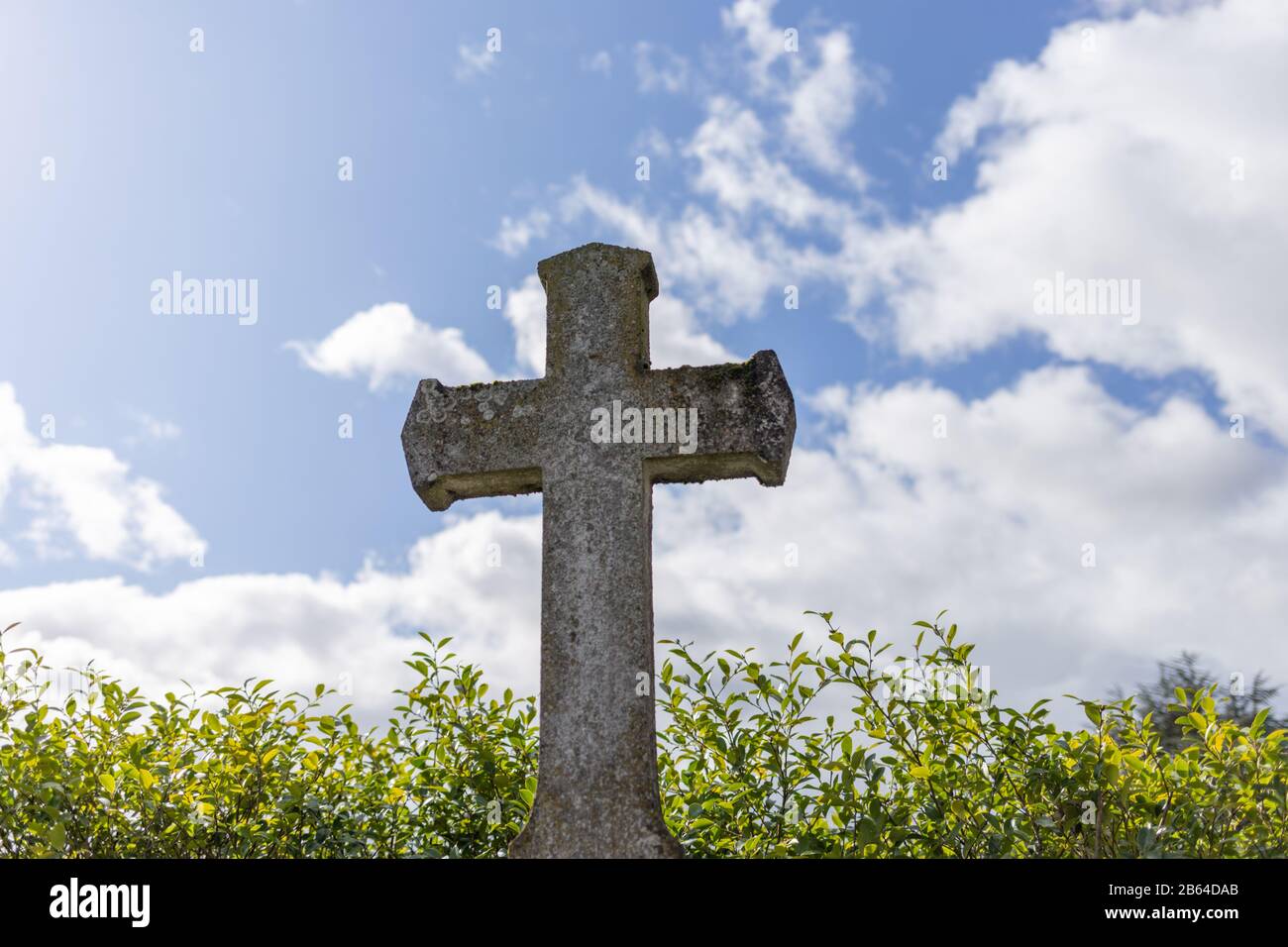 grey grave stone cross standing alone in Cemetery, blue sky background