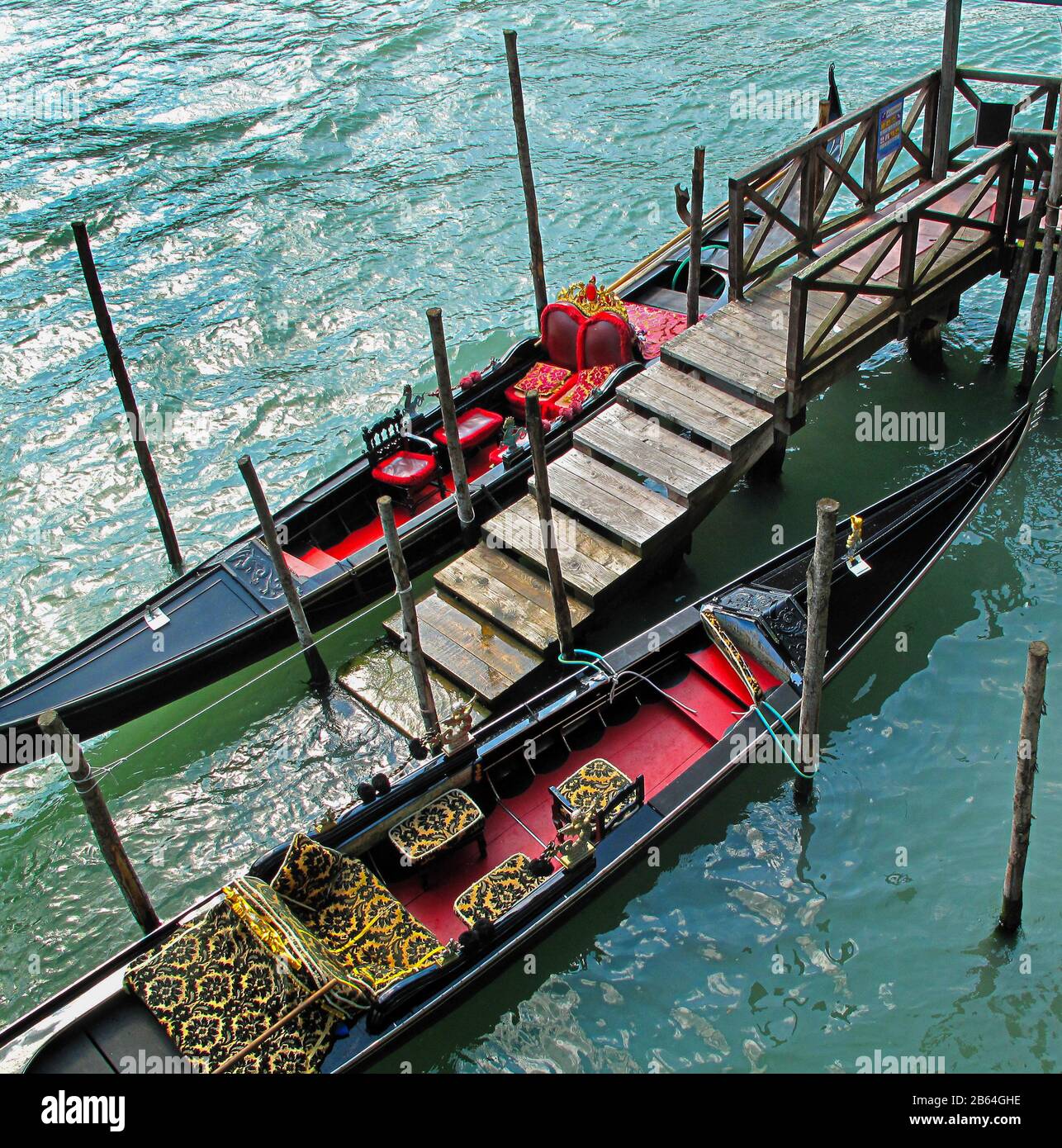 Elevated shot of two gondolas moored tied to landing stage steps on the venice canal waterways. Venice Italy Stock Photo
