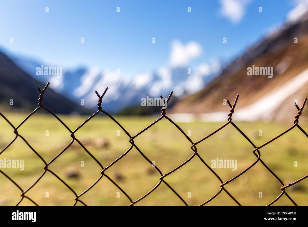 fence with metal bars and barbed wire on the background of blurred ...