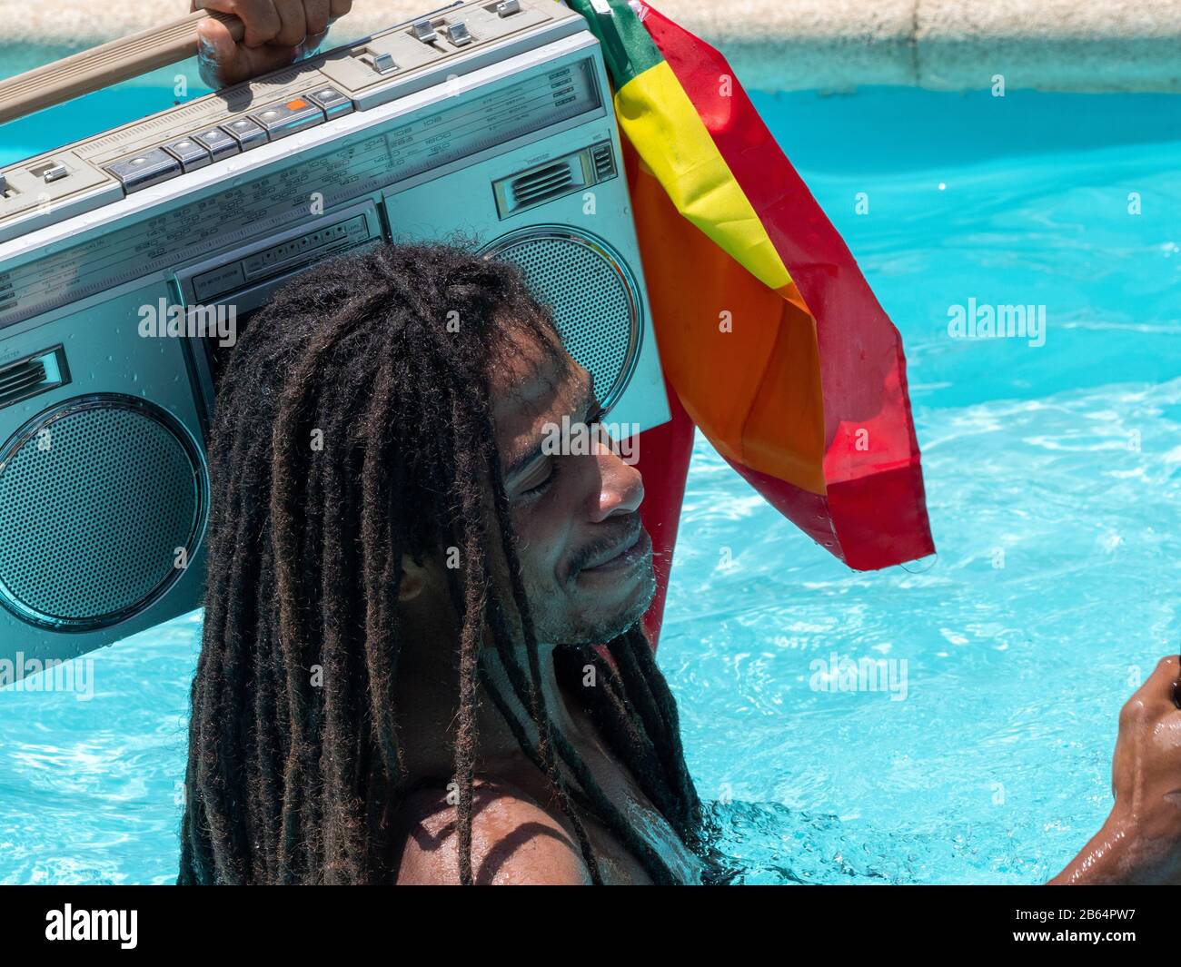 Stock photo of a black guy with dreadlocks in the pool with a cassette on  his shoulder and smiling. Lifestyle Stock Photo - Alamy