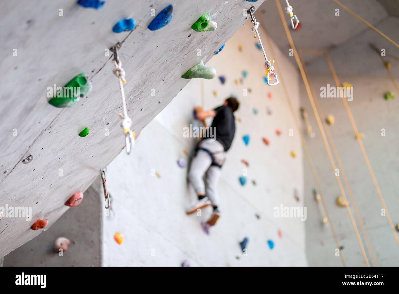 man climbing on practical wall indoor, securing carabiners and rope Stock Photo Alamy