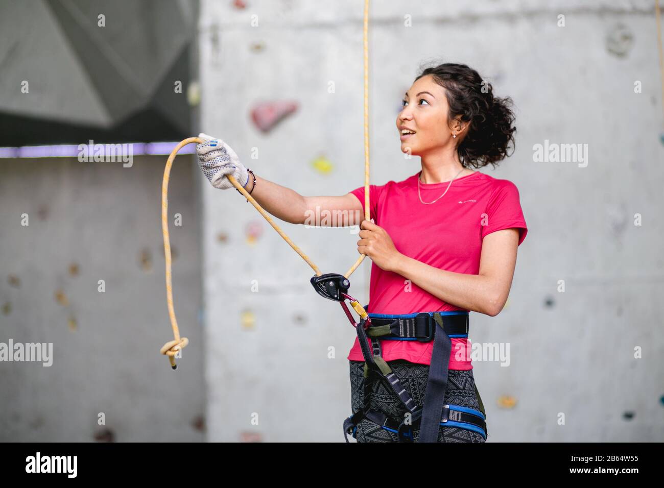 Portrait of beautiful woman rock climber belaying another climber with
