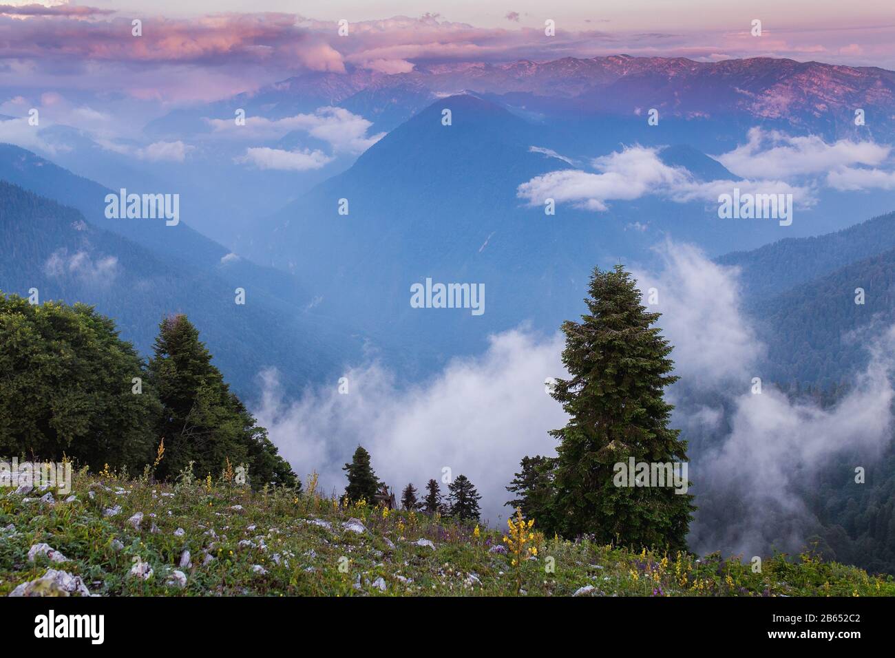 Panorama. Russia, the Caucasus Mountains, Adygea. Fog creeping birch on mountain slopes cloudy summer evening. Stock Photo