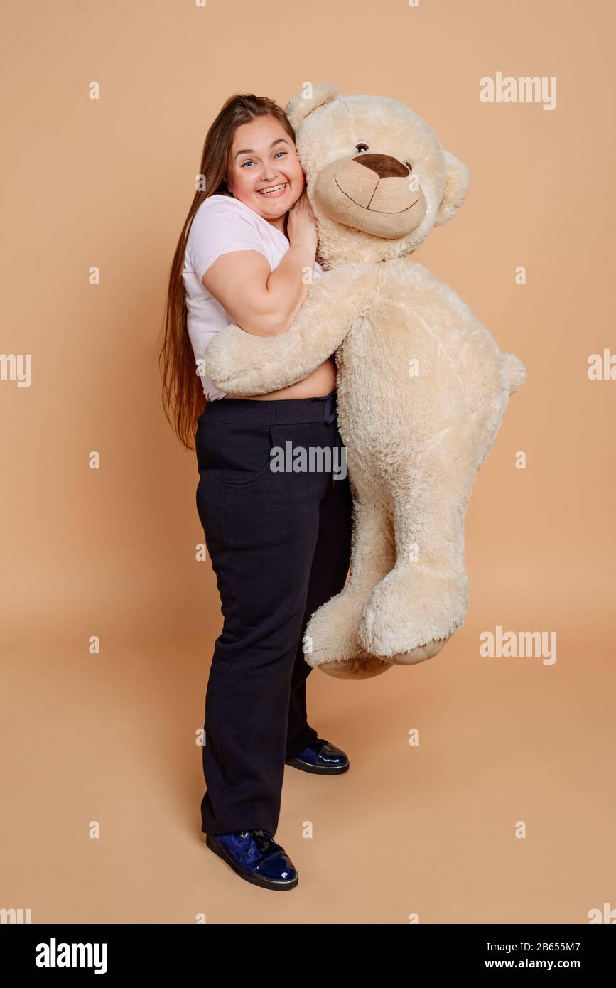 Happy woman hugging Teddy bear on beige background Stock Photo
