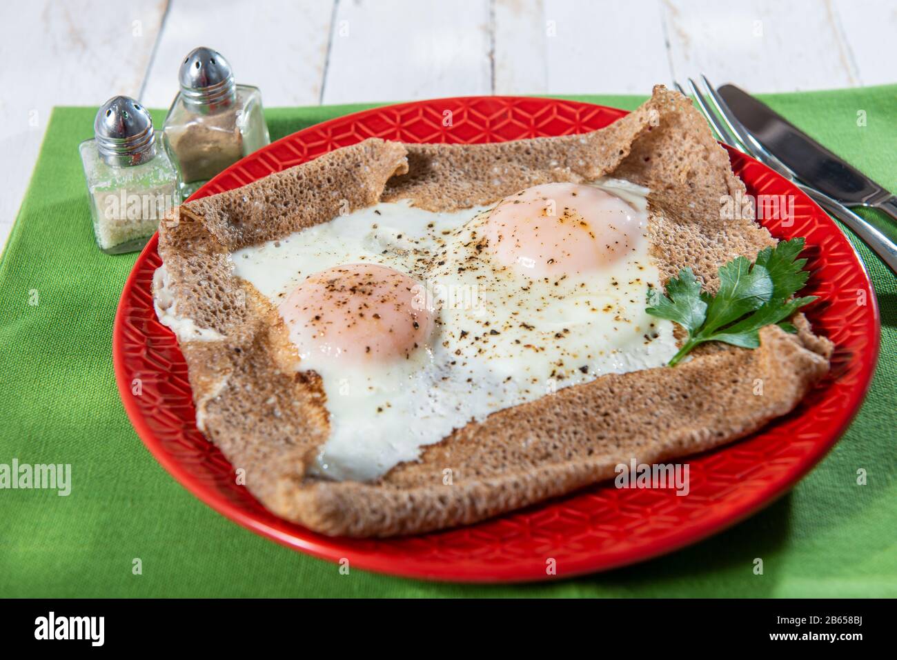 homemade Breton crepe with egg in a red plate Stock Photo