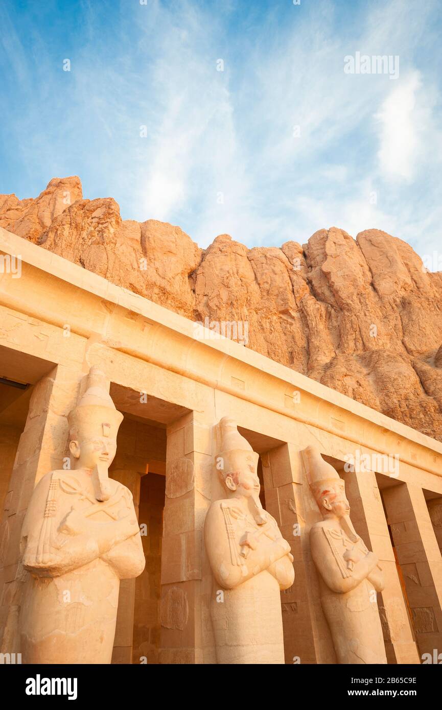 Row of statues of Egyptian god of the underworld Osiris carved into the Deir el-Behari cliffs at the temple of Hatshepsut in West Bank, Luxor, Egypt Stock Photo