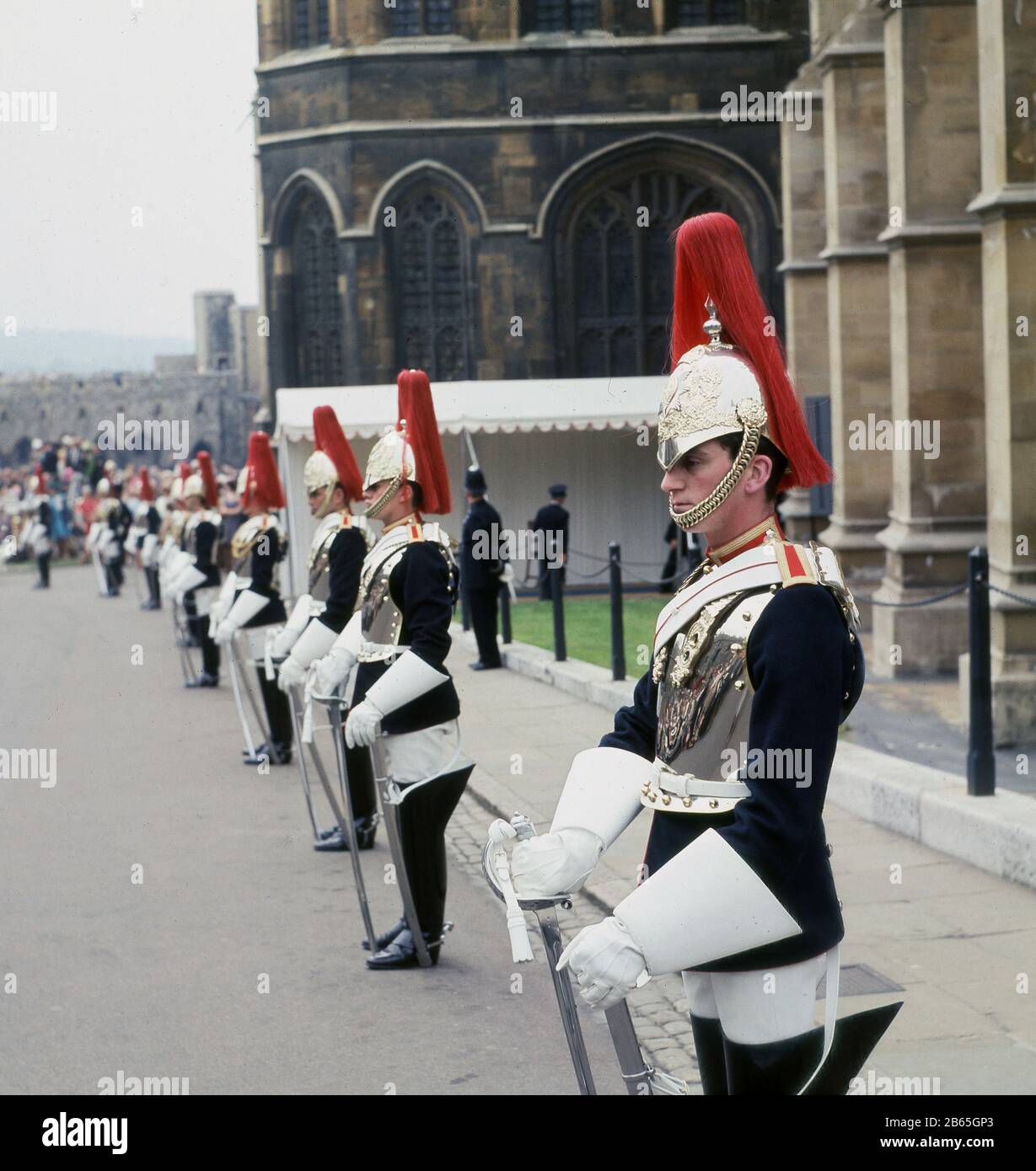 1960s, historical, soliders from the Household Cavalry Mounted Regiment, the Blues in their dark blue tunics, silver cuirasses and helmets with red plumes, standing on ceremony outside Windsor Castle, during the Order of the Garter, the oldest British Order of Chivalry, Berkshire England, UK. The Blues merged with another regiment, the Royal Dragoons in 1969. Stock Photo