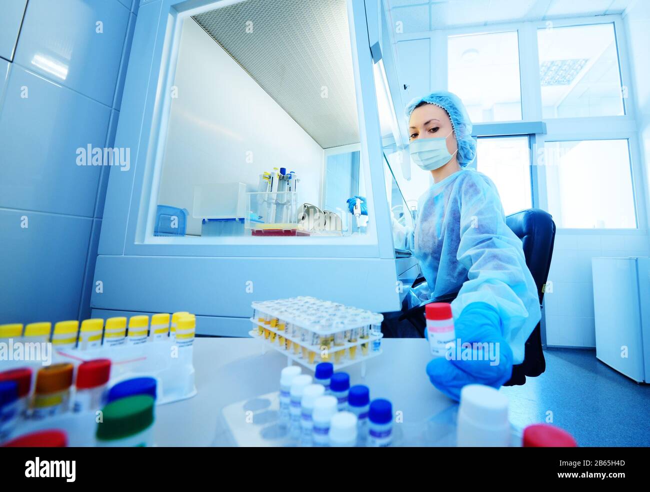 female scientist in a protective medical mask and rubber gloves makes PCR DNA tests in a modern chemical and bacteriological laboratory. Stock Photo