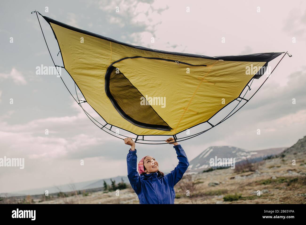 woman in the mountains in a national Park sets up a tent in the camp Stock Photo