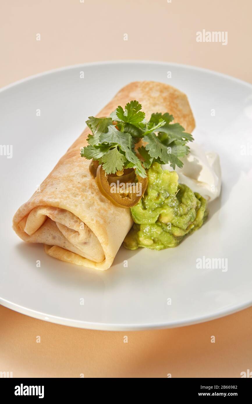 Homemade pancake roll with spicy guacamole and white sauces. Stock Photo