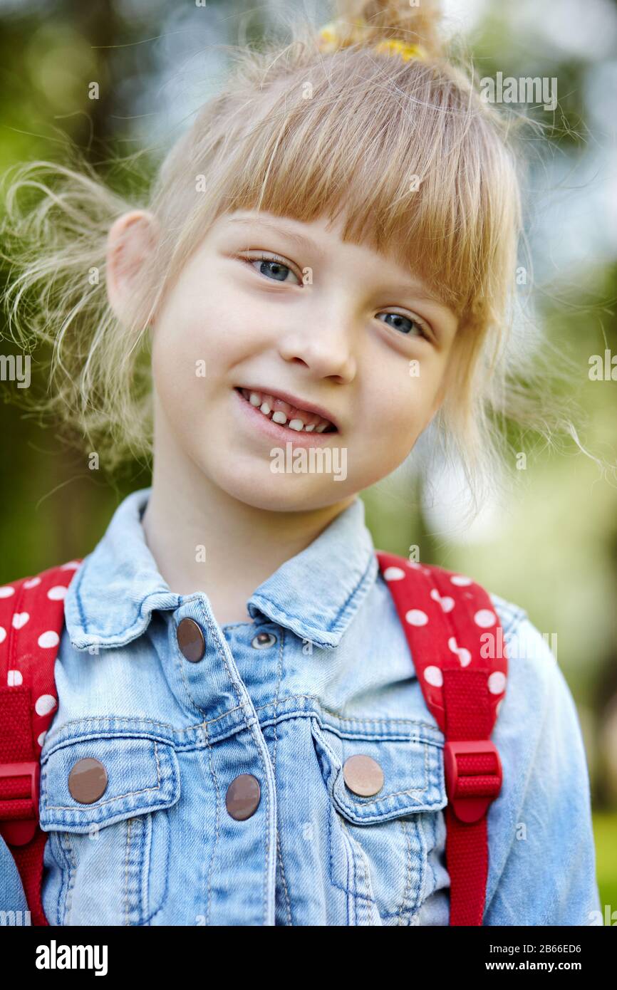 Cheerful child in blue trendy denim jaket posing outdoors. Caucasian young girl enjoys a bright summer or spring lifestyle Stock Photo