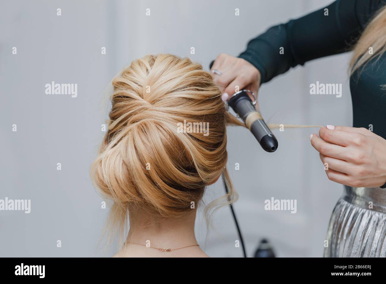 closeup of professional hairdresser hands doing beauty hairstyle ala