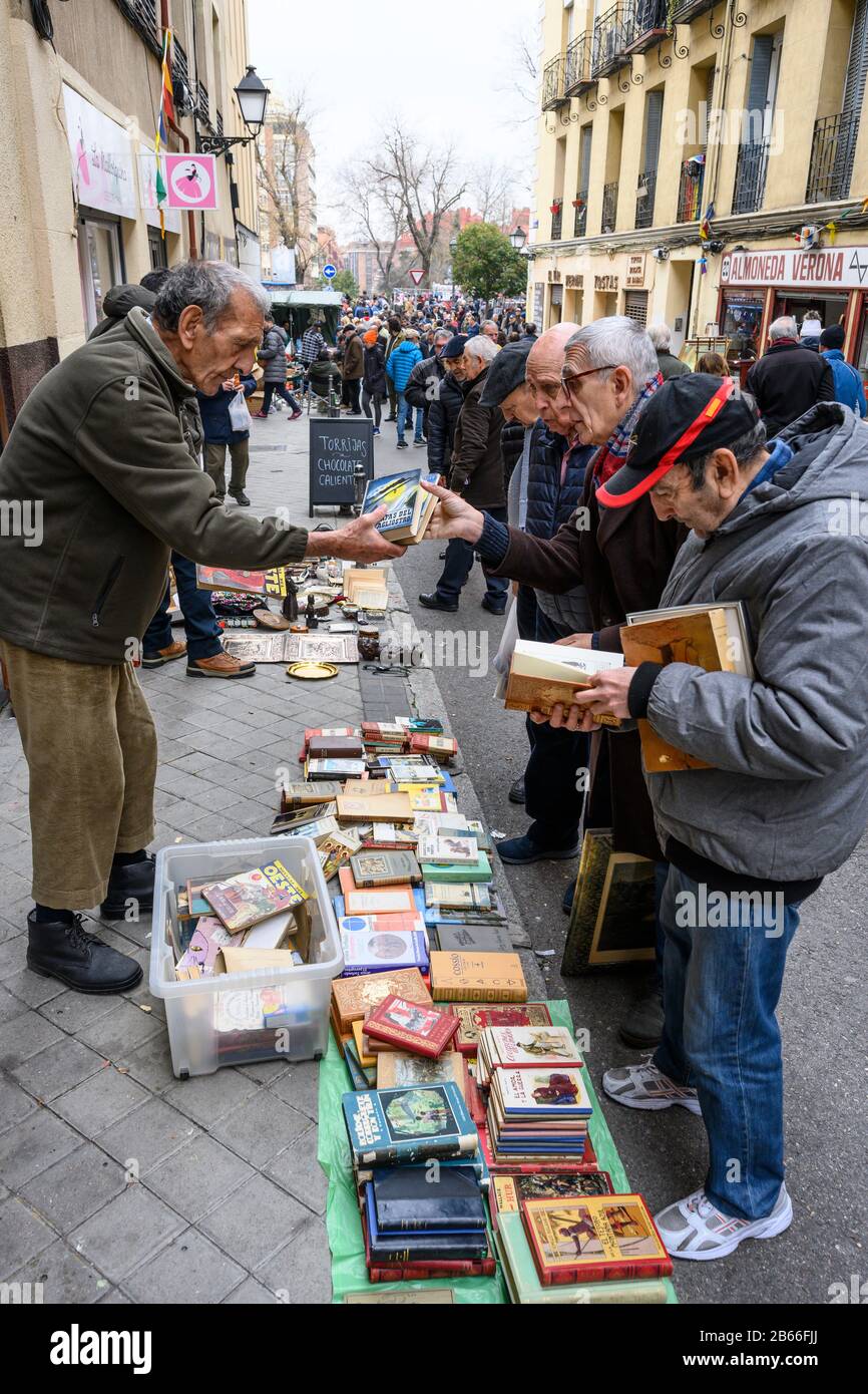Bargain hunters browsing books in the Rastro flea market around the
