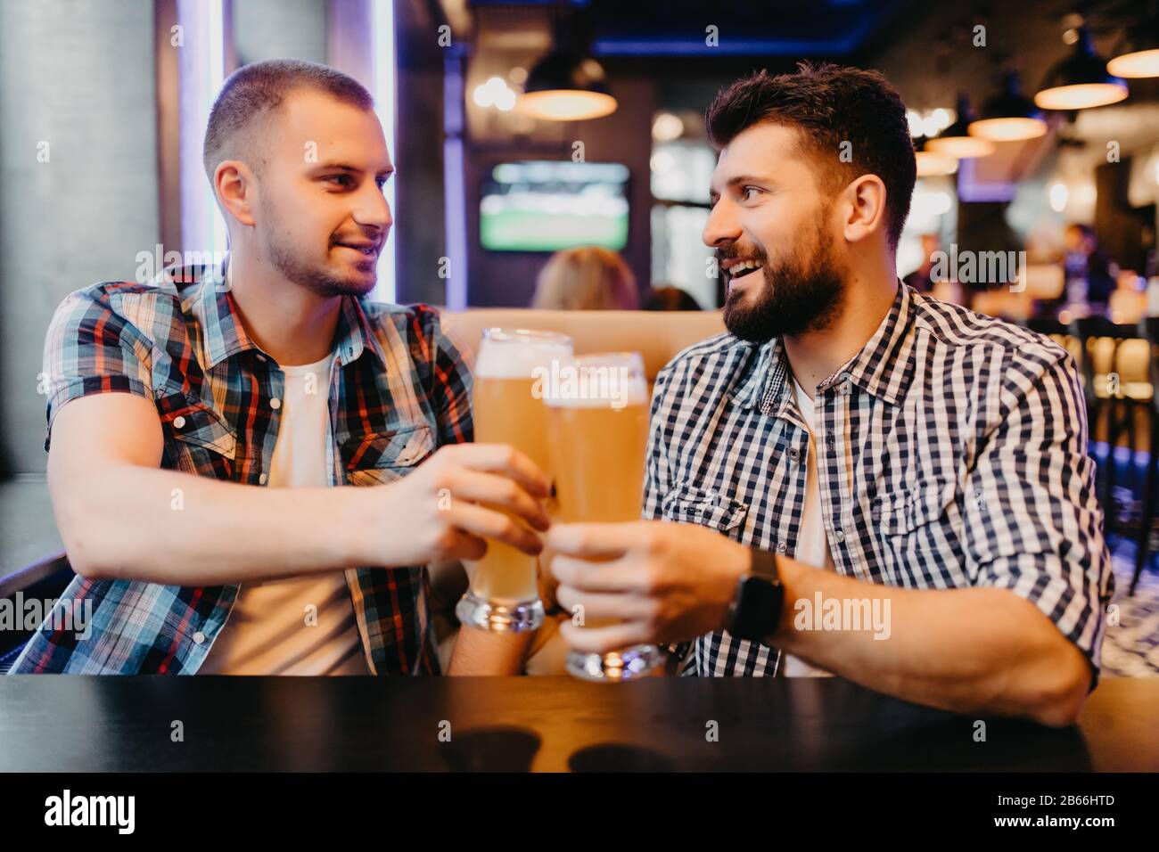 Two men drinking beer in bar, clinking beer have fun in pub Stock Photo ...