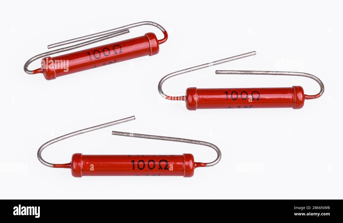 Cylindrical carbon power resistors with bent lead wires on white background. Group of red passive two terminal electrical components. Electrotechnics. Stock Photo