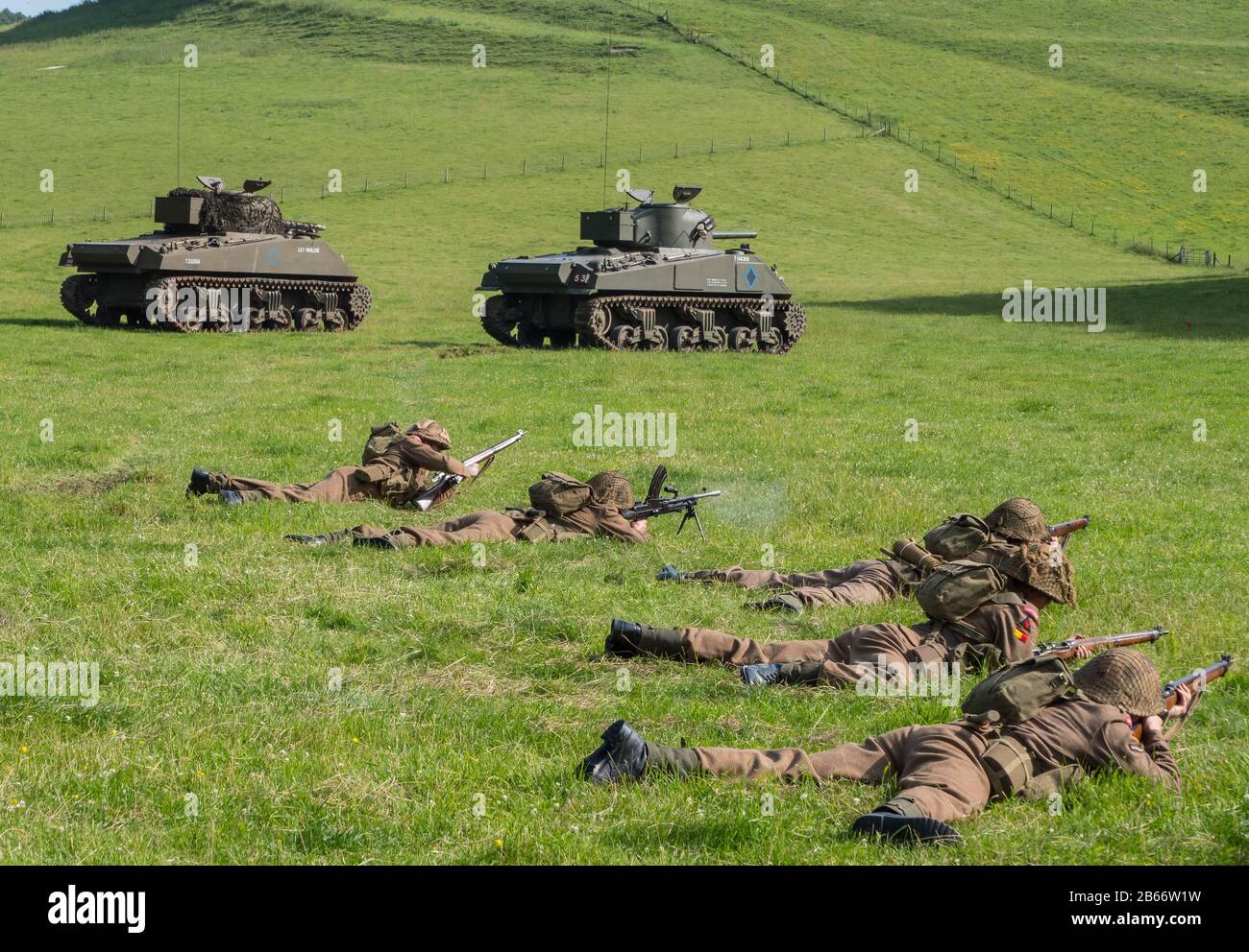 Current soldiers of the Royal Anglian Regiment in WW2 kit performing an infantry platoon attack re-enactment with the support of Sherman tanks. Stock Photo