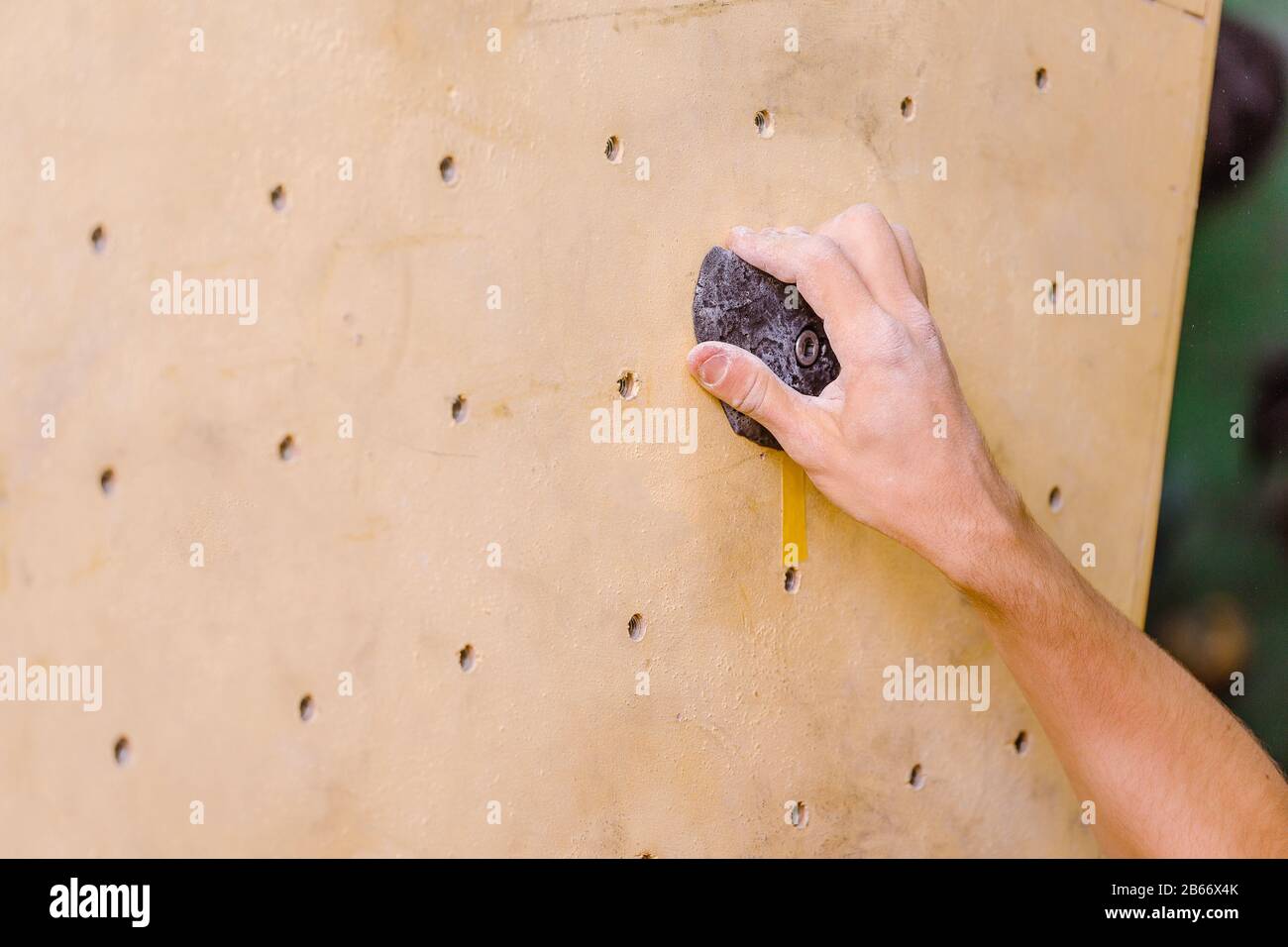 Closeup of man's hand on handhold on artificial climbing wall, thumbs with magnesia Stock Photo