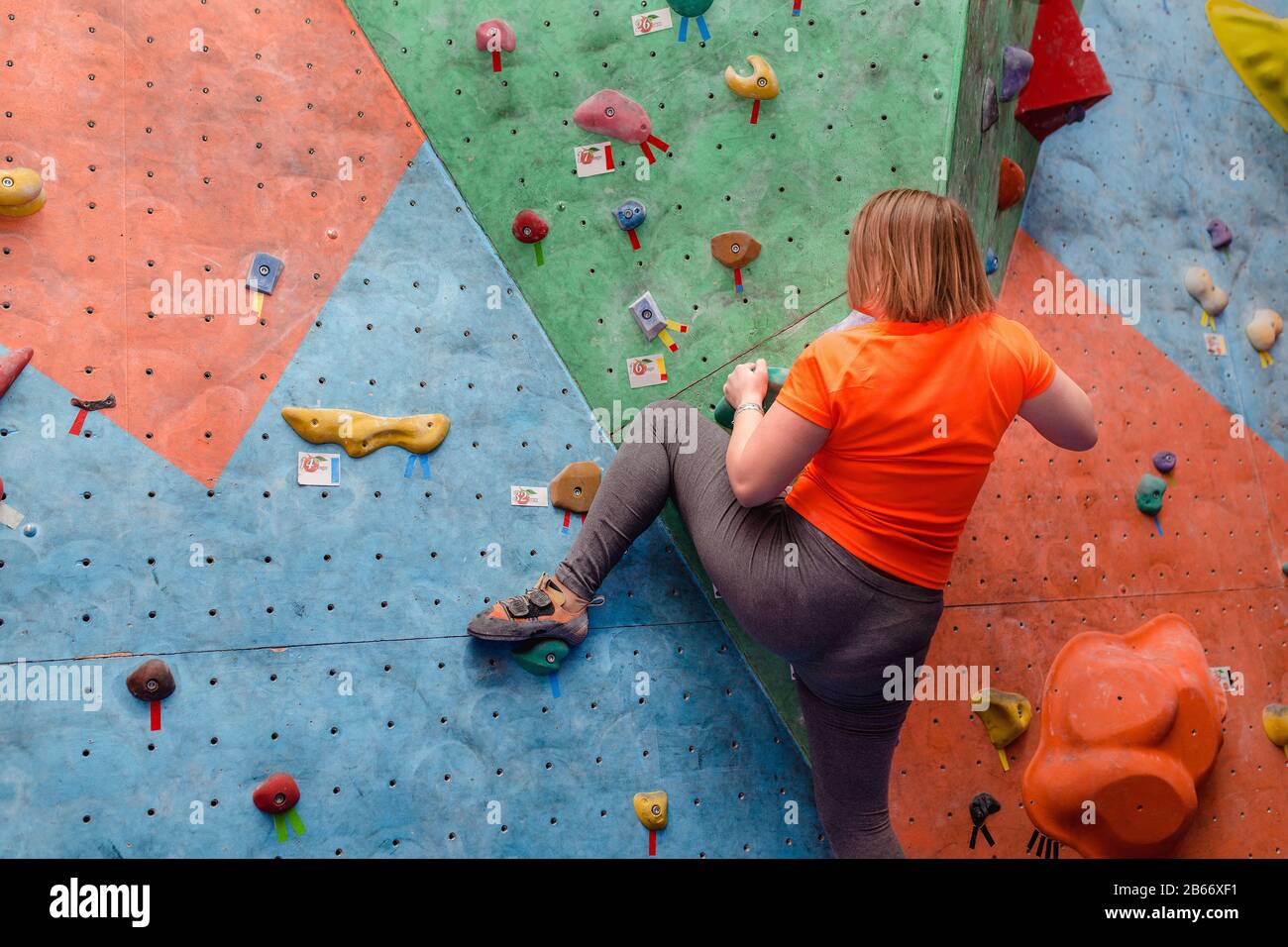 Unrecognizable fat woman in a bad physical shape has been climbing at the bouldering wall and believe in her abilities to lose weight Stock Photo