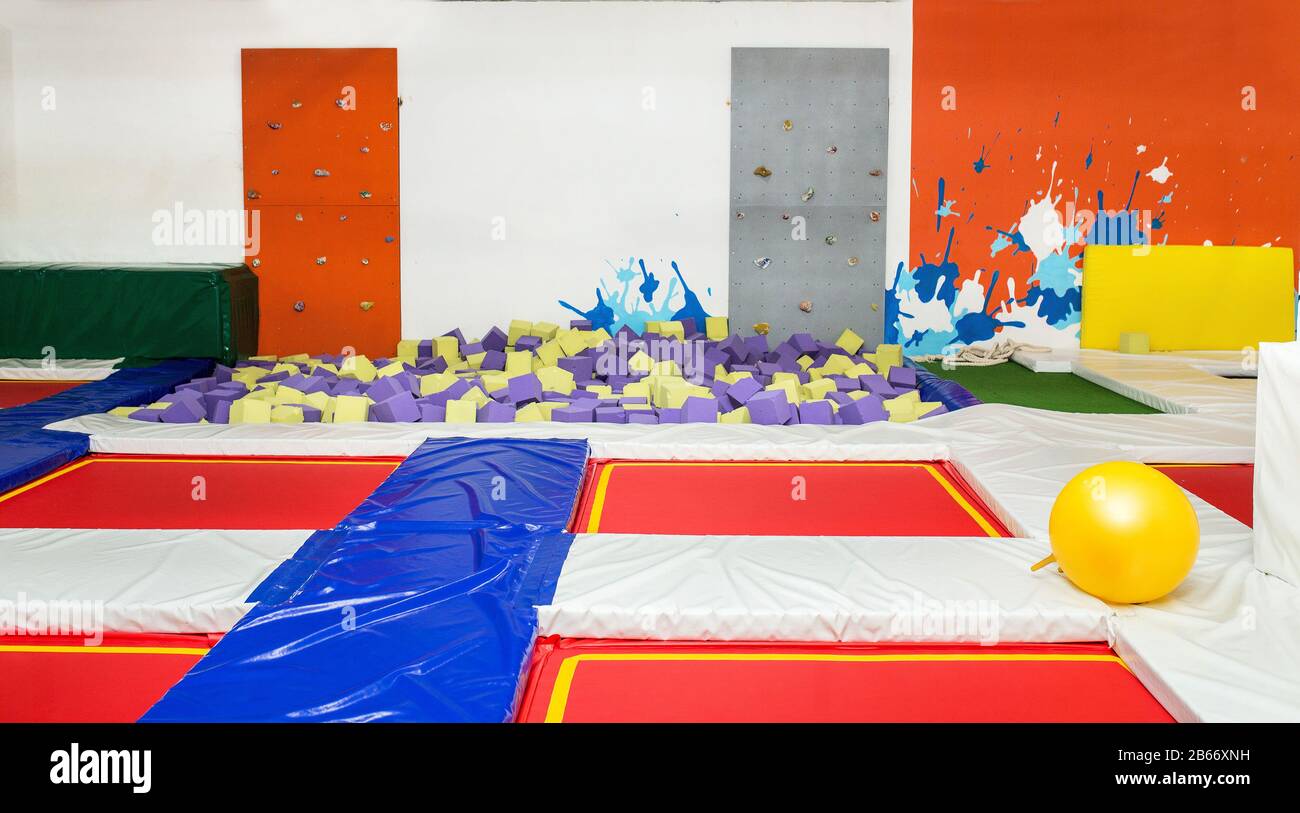 Colorful interior of a children's sports complex with trampolines, climbing wall and a foam pit