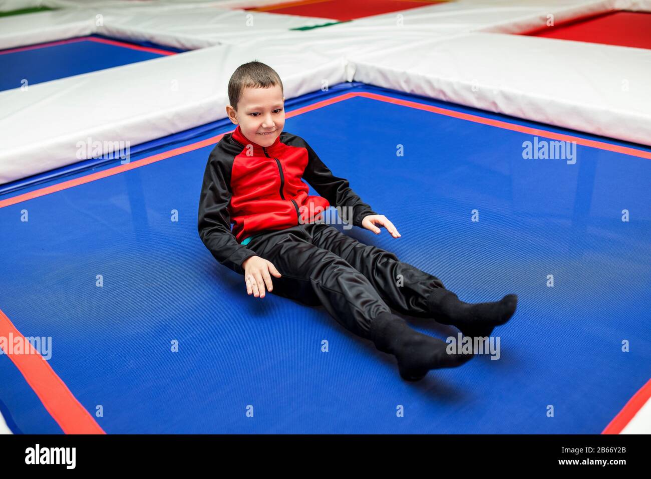 Happy child boy in colorful costume relaxing on trampoline in sport