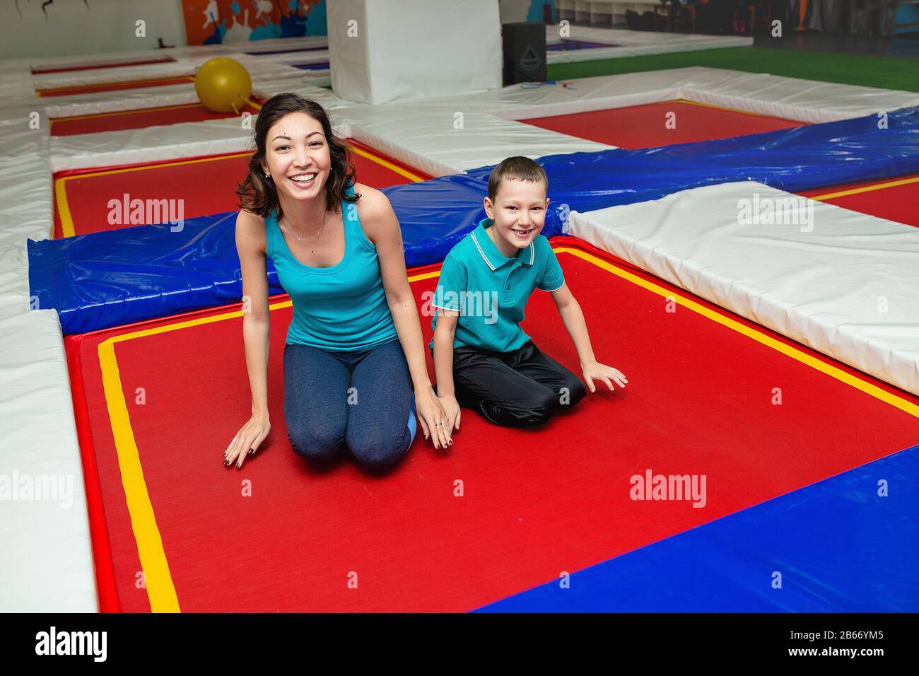Mom with son is stretching on the floor on mats in the fitness gym and