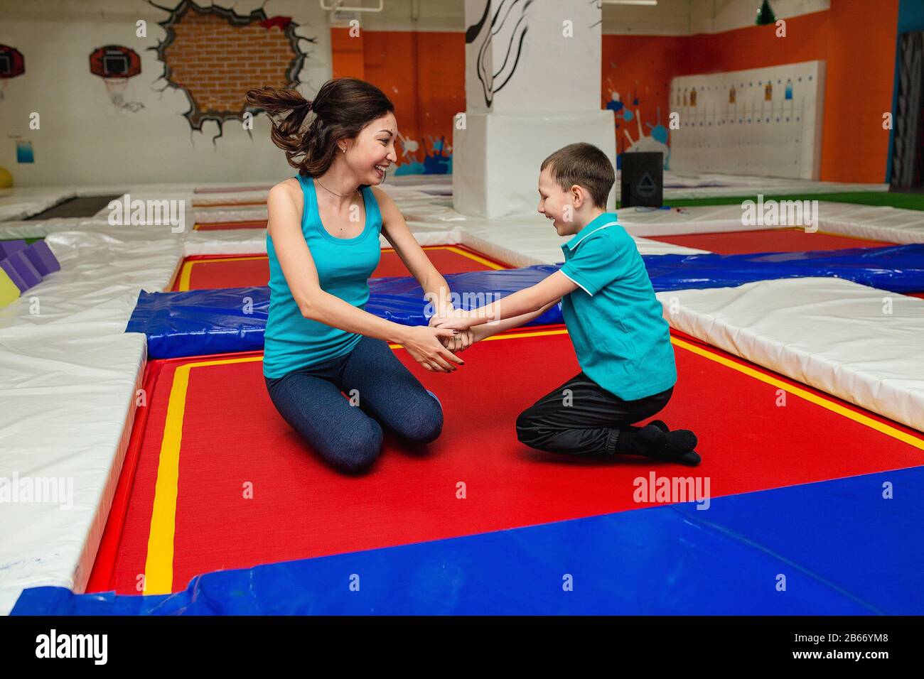 Mom with son is stretching on the floor on mats in the fitness gym and